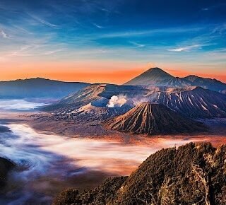 Panoramic sunrise view of Mount Bromo and surrounding volcanic peaks in East Java, Indonesia, with vibrant sky colors and misty caldera, popular destination for Ijen and Bromo 4-day tours