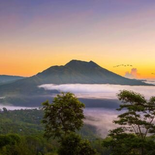 Stunning sunrise over Mount Batur volcano with mist-covered hills in Kintamani, Bali.