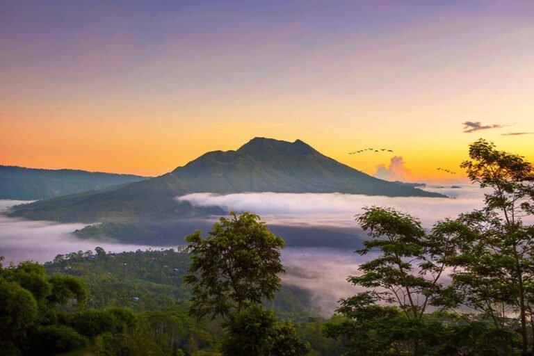 Stunning sunrise over Mount Batur volcano with mist-covered hills in Kintamani, Bali.